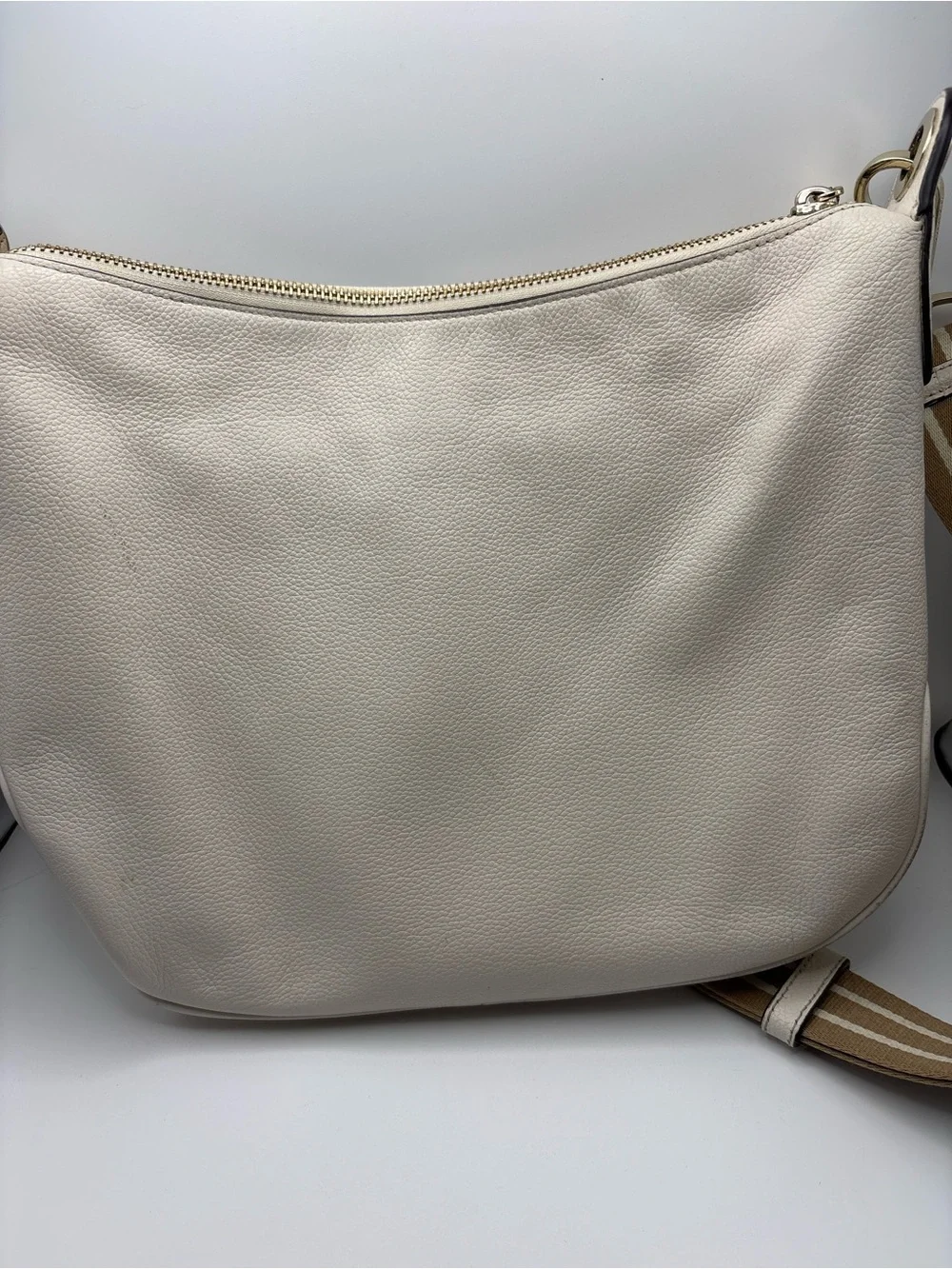 Kate Spade New York cream leather crossbody bag featuring a striped webbing Stra